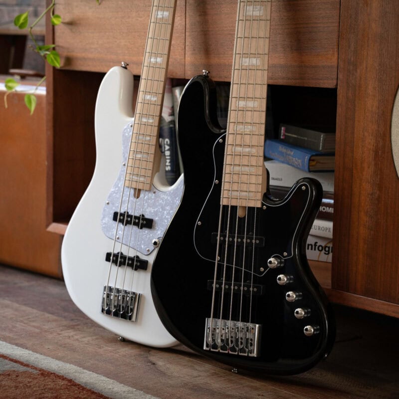Electric bass guitars in black and white leaning against a wooden shelf at The Music Outlet in Swords, Dublin.