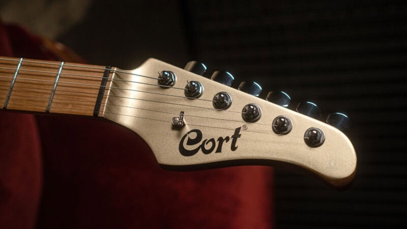 Cort electric guitar headstock with tuning pegs and logo, close-up shot.