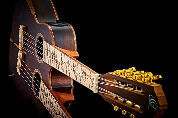 Highly polished acoustic guitar with intricate fretboard design and gold tuning pegs, positioned against a black background, showcasing craftsmanship and musical elegance.